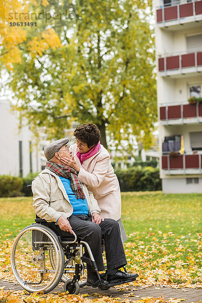 Seniorenfrau sieht Mann im Rollstuhl an