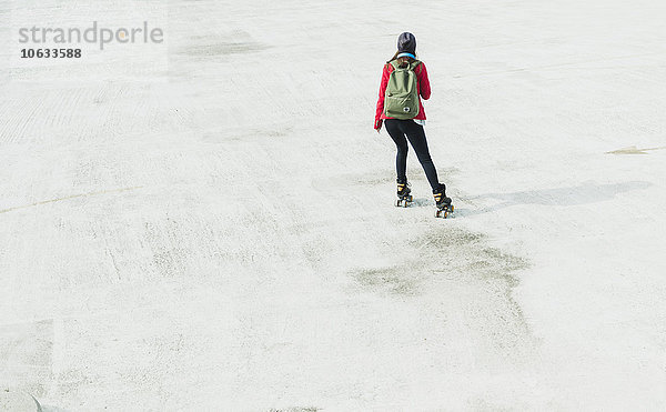 Junge Frau mit Rucksack Inline-Skating auf Parkebene