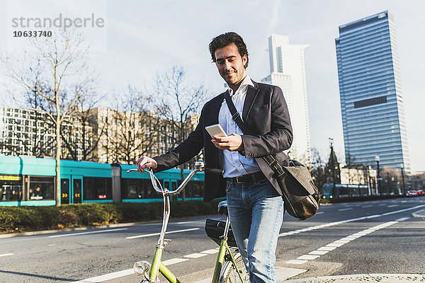 Deutschland  Frankfurt  Jungunternehmer in der Stadt mit dem Fahrrad  per Handy