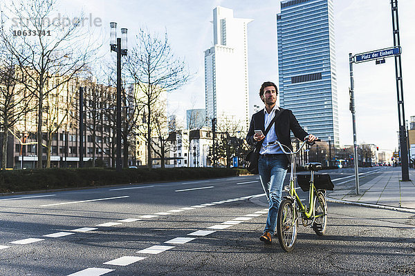 Deutschland  Frankfurt  Jungunternehmer in der Stadt mit dem Fahrrad  per Handy