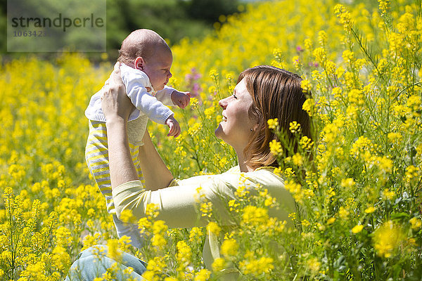 Mutter mit ihrem kleinen Mädchen auf gelb blühendem Blumenfeld