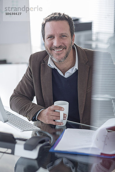 Porträt eines lächelnden Geschäftsmannes am Schreibtisch