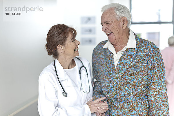 Arzt mit glücklicher älterer Patientin auf dem Krankenhausboden