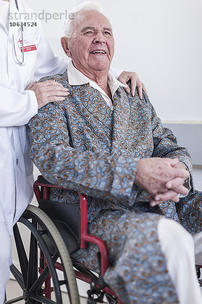 Arzt und lächelnder älterer Patient im Rollstuhl