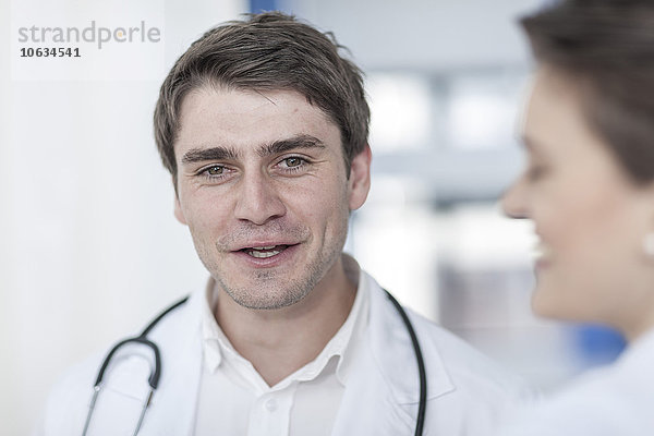 Lächelnder Arzt im Gespräch mit Frau im Krankenhaus