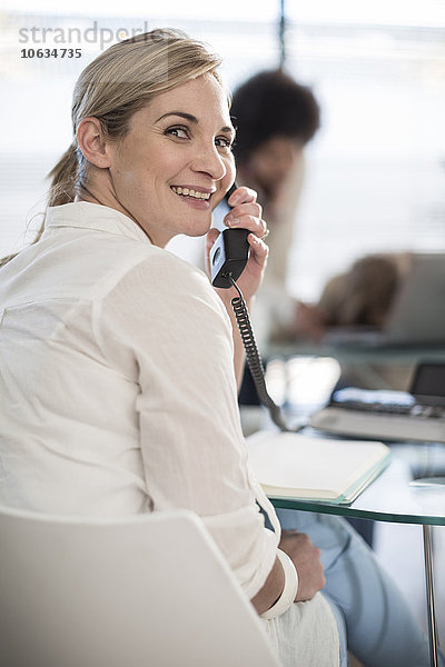 Lächelnde Frau am Telefon im Büro