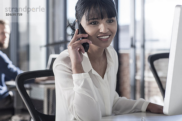 Junge Frau am Telefon  die im Büro arbeitet.