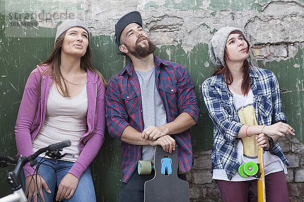 Drei stilvolle Freunde mit Skateboards  die nach oben schauen.