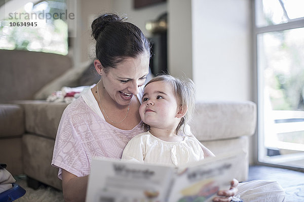 Mutter und kleines Mädchen zu Hause beim Betrachten des Buches