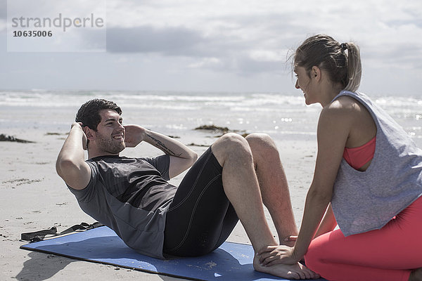 Junger Mann und Frau beim Training am Strand