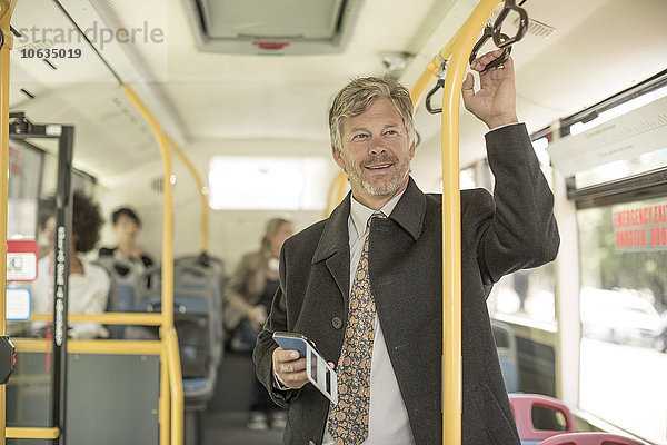 Erwachsener Mann nimmt Stadtbus  hält Smartphone