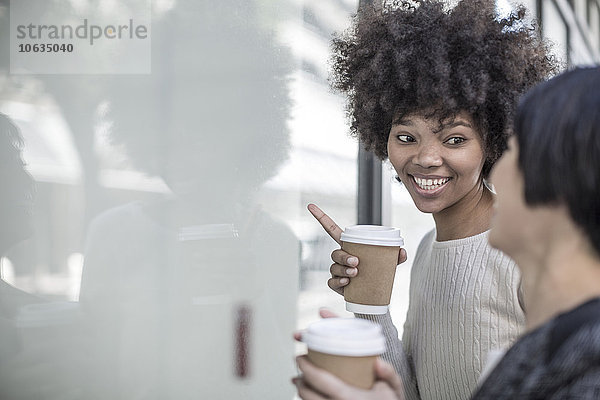 Zwei junge Frauen mit Kaffee im Schaufenster