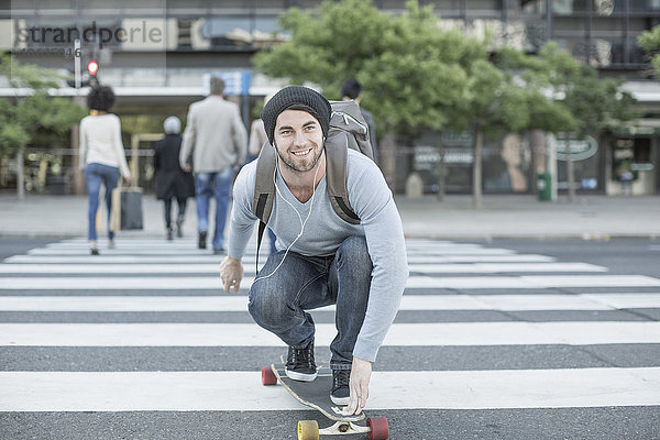 Junger Mann beim Skateboarden auf Zebrastreifen