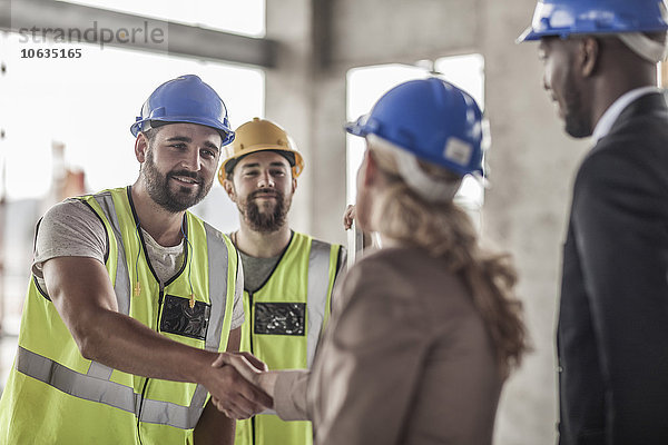 Bauarbeiter und Führungskraft beim Händeschütteln auf der Baustelle