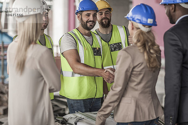 Bauarbeiter und Führungskraft beim Händeschütteln auf der Baustelle