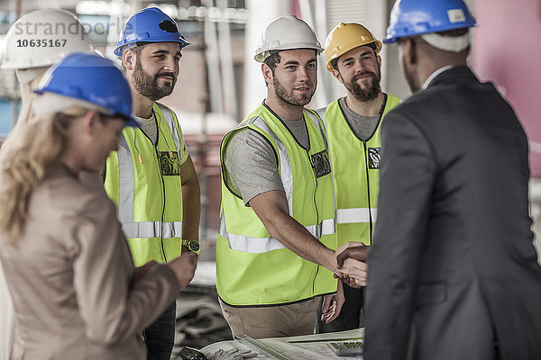 Bauarbeiter und Führungskraft beim Händeschütteln auf der Baustelle