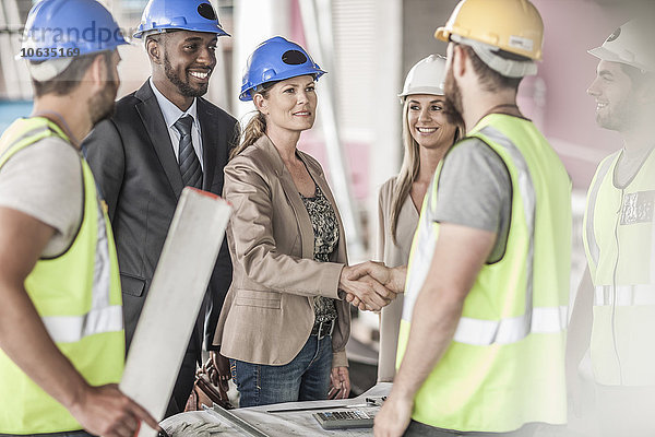 Bauarbeiter und Führungskraft beim Händeschütteln auf der Baustelle