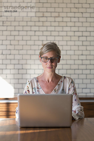 Frau am Tisch sitzend mit Laptop