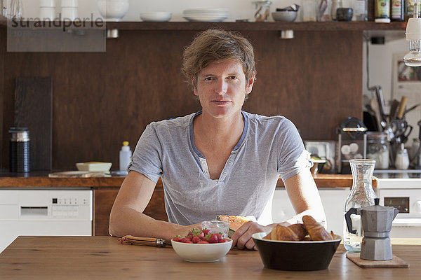 Junger Mann am Esstisch mit Frühstück  Porträt