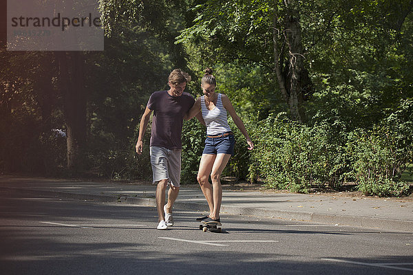 Junger Mann hilft Frau beim Schlittschuhlaufen