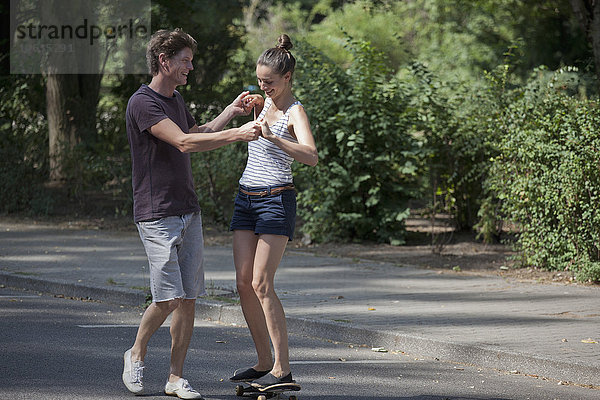 Junger Mann lehrt Frau das Skaten