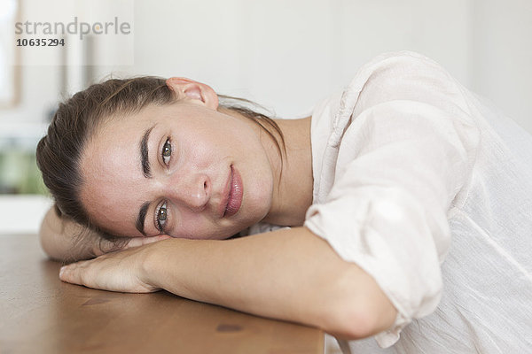 Junge Frau auf Tisch gelehnt  Porträt