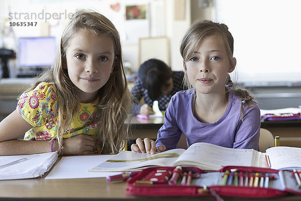 Drei Mädchen mit Büchern im Klassenzimmer