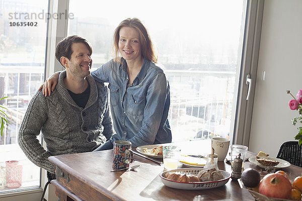 Paar sitzend am Esstisch mit Frühstück