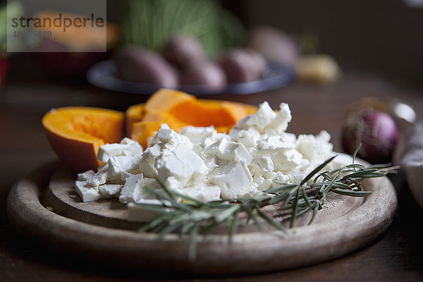 Nahaufnahme von Schafskäse mit Rosmarin auf dem Schneidebrett