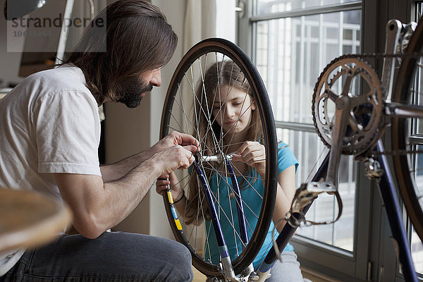 Vater und Tochter reparieren gemeinsam zu Hause das Fahrrad