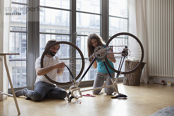 Vater und Tochter reparieren das Fahrrad gemeinsam zu Hause