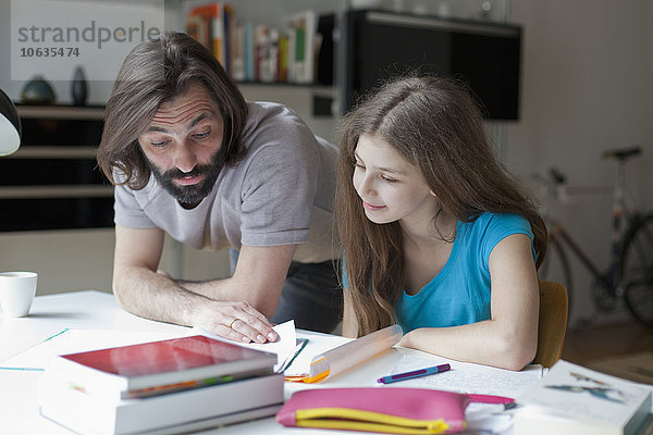 Vater hilft der Tochter bei den Hausaufgaben am Tisch