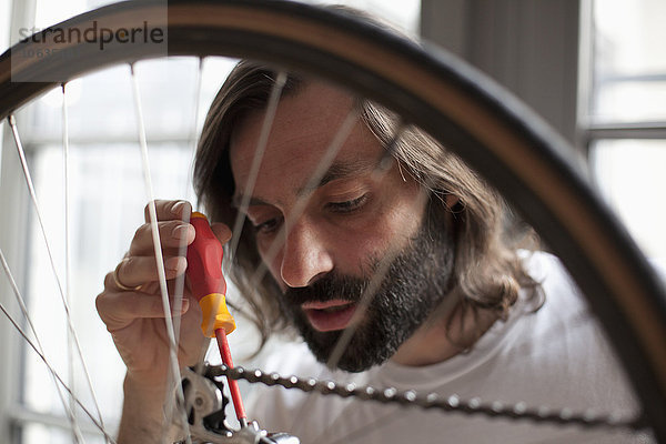 Mittlerer Erwachsener Mann repariert Fahrrad zu Hause