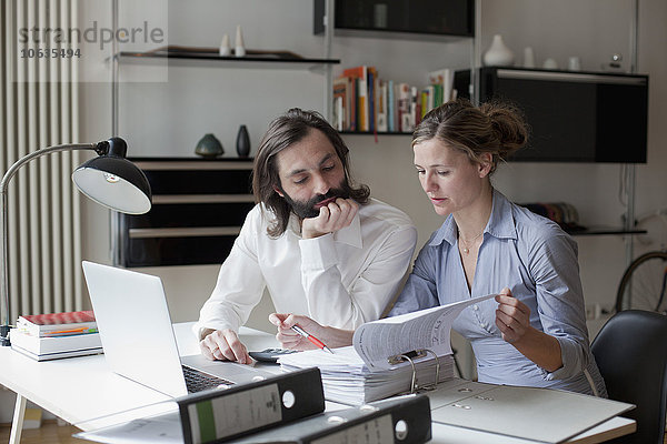 Mittleres erwachsenes Paar  das zu Hause arbeitet