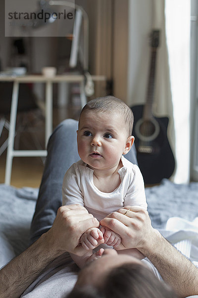 Süßes kleines Mädchen sitzt auf dem Vater zu Hause.