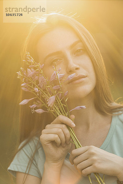 Porträt einer schönen Frau mit Blumen an einem sonnigen Tag
