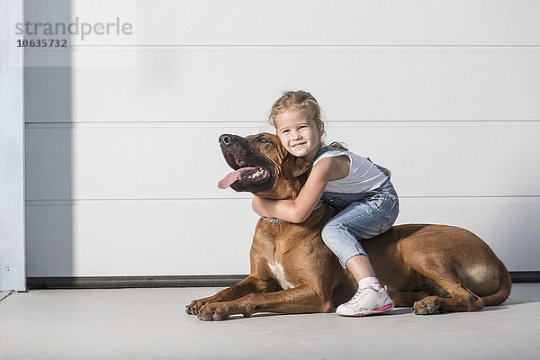 Porträt eines süßen Mädchens  das auf einem Hund im Freien sitzt.