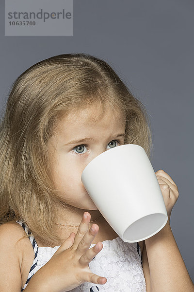 Süßes Mädchen trinkt Kaffee vor grauem Hintergrund