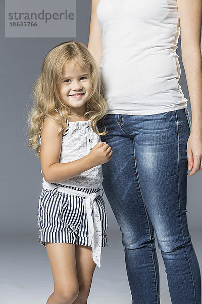 Porträt eines glücklichen Mädchens mit Mutter auf grauem Hintergrund