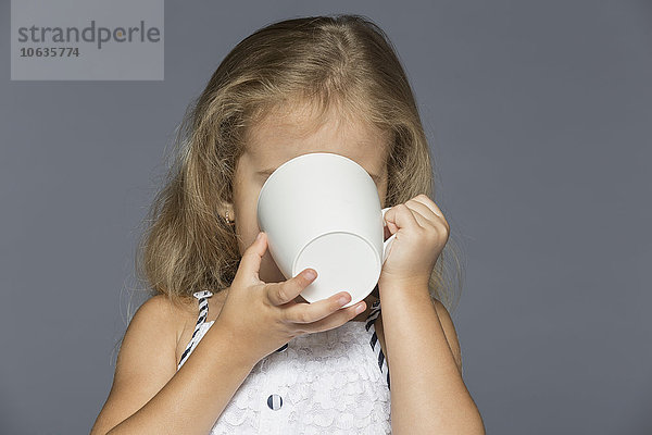 Mädchen trinkt Kaffee vor grauem Hintergrund