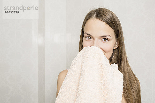 Porträt einer lächelnden Frau mit Handtuch im häuslichen Badezimmer