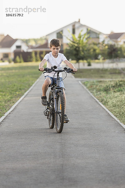 Junge Radfahren auf dem Fußweg