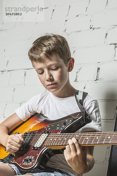 Junge spielt zu Hause Gitarre gegen Wand