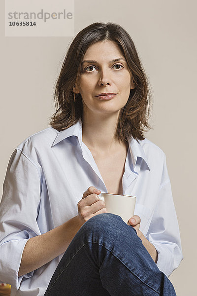 Porträt einer selbstbewussten Frau mit Kaffeetasse auf weißem Hintergrund