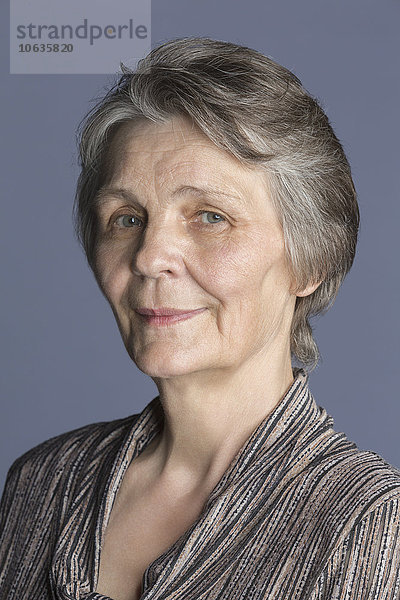 Porträt der lächelnden Seniorin vor violettem Hintergrund