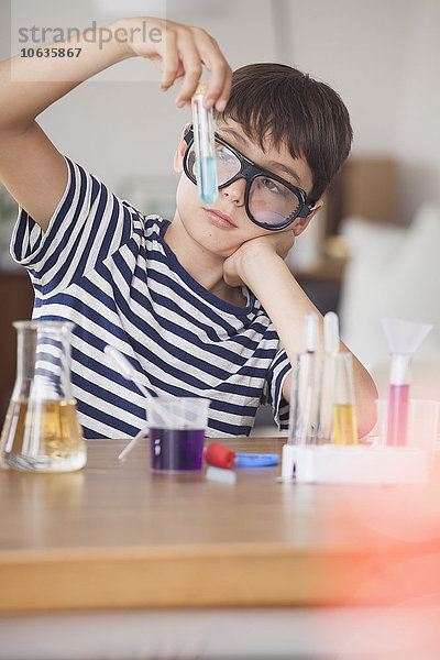 Junge mit Schutzbrille beim Blick auf das Reagenzglas im Haus