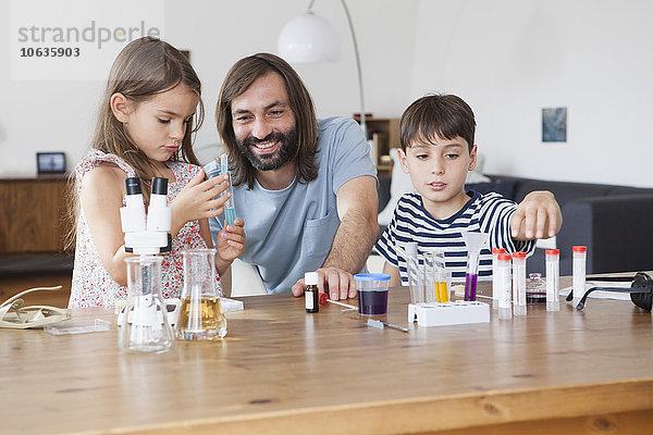 Vater und Kinder beim wissenschaftlichen Experiment auf dem Tisch im Haus