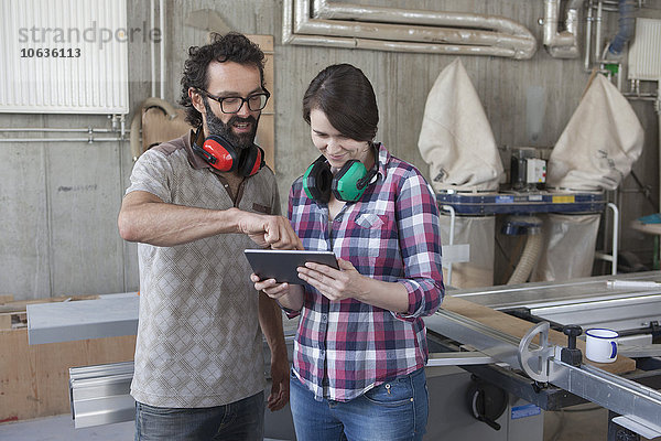 Mittlere erwachsene Schreiner diskutieren über digitale Tabletten in der Werkstatt