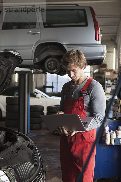 Mittlerer Erwachsener Mechaniker mit Laptop in der Garage