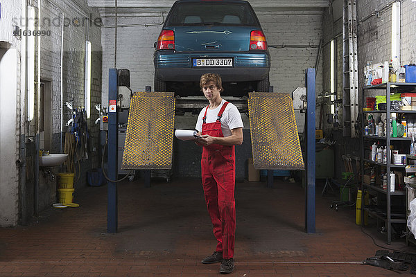 Porträt eines selbstbewussten Mechanikers mit Klemmbrett in der Garage